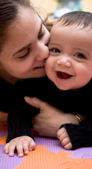 A mother and child laugh together in a preschool setting